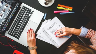 Frau arbeitet mit Laptop und Notizblock